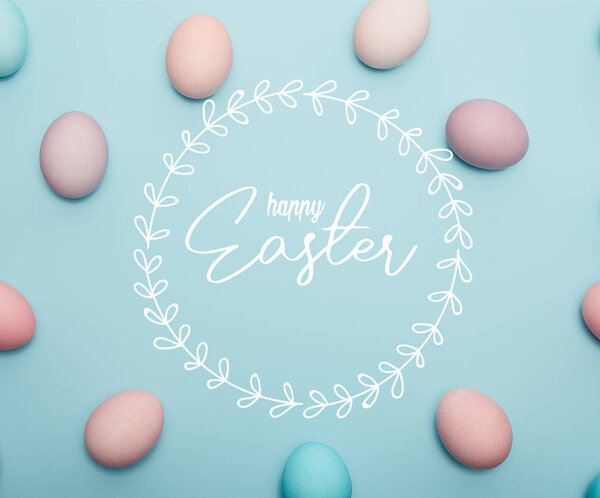 top view of painted multicolored eggs on blue background with happy Easter lettering