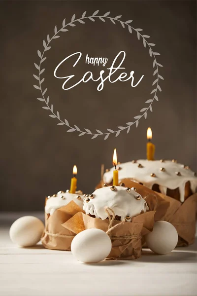 传统的复活节蛋糕与燃烧的蜡烛和白色的鸡蛋在棕色的背景与快乐的复活节字母 — 图库照片