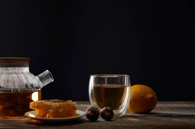 siyah izole ahşap masa üzerinde çiçekaçan çay, cam, limon ve petek ile şeffaf çaydanlık
