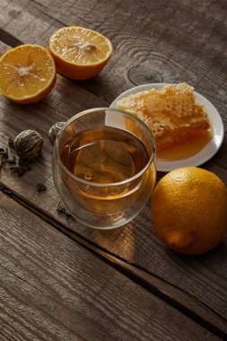 ahşap masada çin çiçekaçan çay, limon ve petek cam 