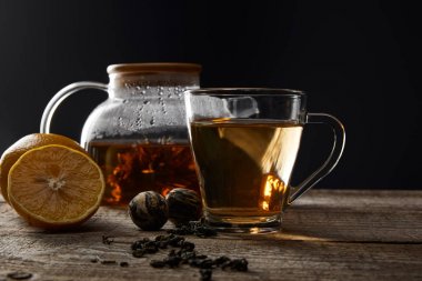 şeffaf çaydanlık ve siyah izole limon ile ahşap masada geleneksel çiçekçay ile fincan