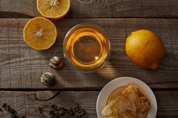 top view of chinese blooming tea in glass, lemons and honeycomb on wooden table