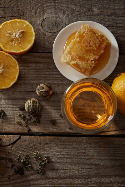 top view of chinese blooming tea in glass, lemons and honeycomb on wooden table