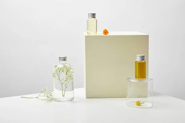 白色桌子上的有机化妆品和鲜花的瓶子在灰色背景 — 图库照片