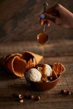 kasede waffle parçaları ile lezzetli dondurma üzerine karamel döken kadın kısmi görünümü 