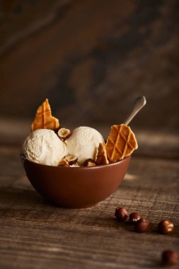 ahşap masada kase waffle ve fındık parçaları ile lezzetli dondurma kepçe