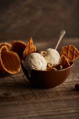 ahşap masada kase waffle ve fındık parçaları ile lezzetli dondurma kepçe