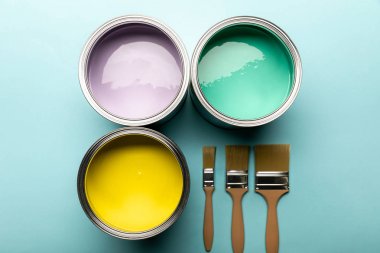 top view of tins with paints and brushes on blue surface clipart