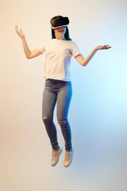 sanal gerçeklik kulaklık mutlu esmer kadın levitating ve bej ve mavi omuz silkme jest gösteren 