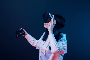 Kiev, Ukrayna - 5 Nisan 2019: Mavi sanal gerçeklik kulaklığı dokunurken joystick tutan esmer kadın 