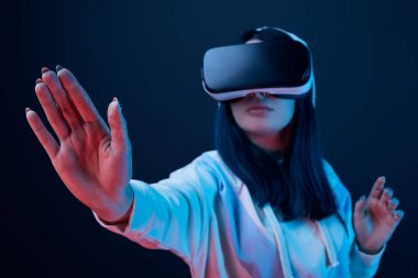 selective focus of girl gesturing while using virtual reality headset on blue  clipart