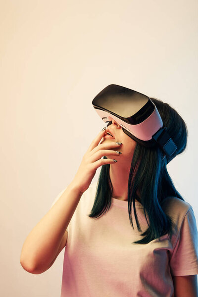 pensive brunette woman wearing virtual reality headset on beige and blue