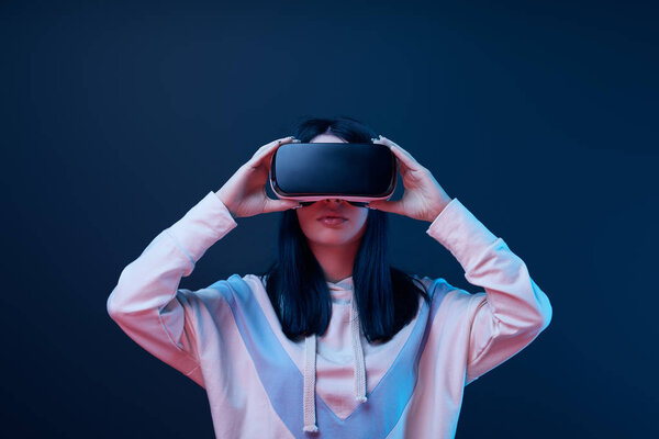 brunette young woman touching virtual reality headset on blue 