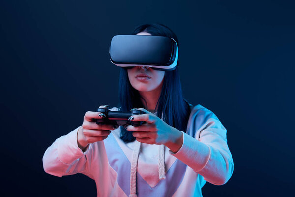КИЕВ, УКРАИНА - 5 апреля 2019 года: Выборочный фокус молодой женщины, играющей в видеоигры в наушниках виртуальной реальности на синем
 