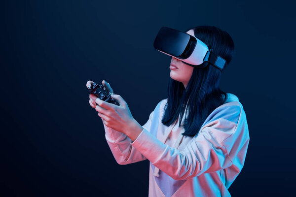 КИЕВ, Украина - 5 апреля 2019 года: Брюнетка держит джойстик, играя в видеоигру в наушниках виртуальной реальности на голубом
 