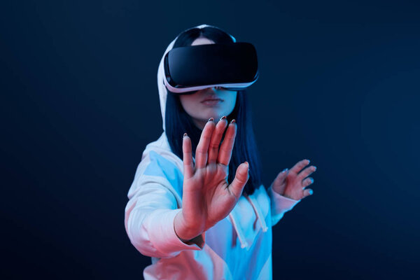 selective focus of woman gesturing while using virtual reality headset on blue 