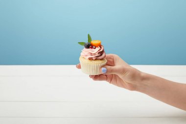mavi izole tatlı cupcake tutan kadın kırpılmış görünümü