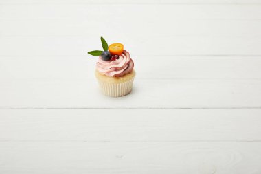 beyaz yüzeyüzerinde üzüm, garnet ve kumquat ile cupcake