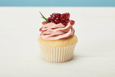 mavi izole beyaz yüzeyüzerinde garnet ve krem ile lezzetli cupcake