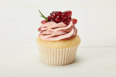 beyaz yüzeyüzerinde krem ve garnet ile lezzetli cupcake