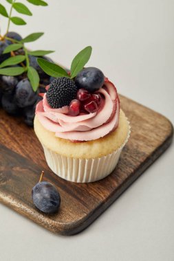 gri izole kesme tahtası üzerinde krem ve üzüm ile cupcake