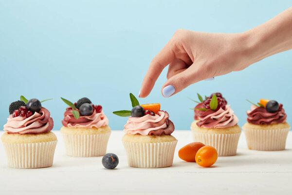 partial view of woman with sweet cupcakes with berries