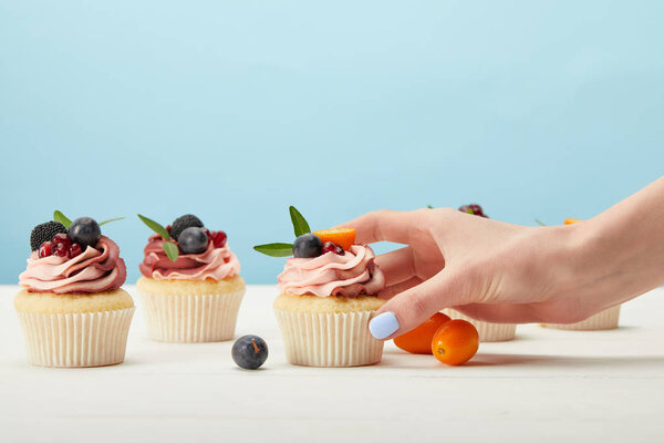 partial view of woman with sweet cupcakes with berries
