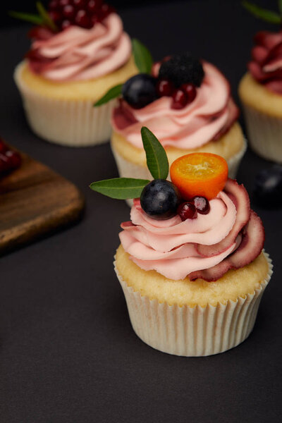 cupcakes with fruits and berries on black surface