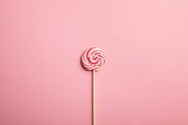 pembe arka plan üzerinde ahşap sopa üzerinde lezzetli çok renkli girdap lolipop üst görünümü