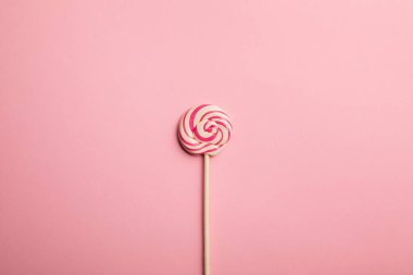 top view of delicious multicolored swirl lollipop on wooden stick on pink background clipart
