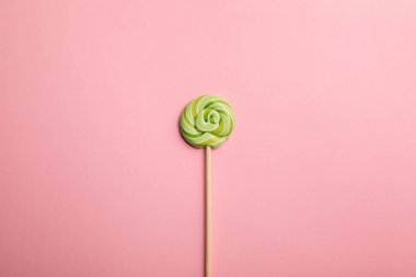 pembe arka plan üzerinde ahşap sopa üzerinde lezzetli yeşil girdap lolipop üst görünümü
