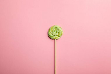 top view of delicious green swirl lollipop on wooden stick on pink background clipart