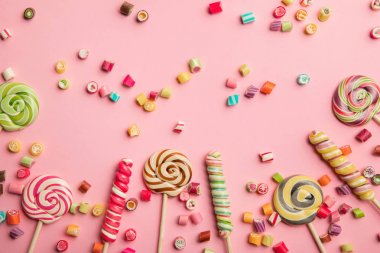 pembe arka plan üzerinde lezzetli çok renkli şekerler ve lolipop üst görünümü