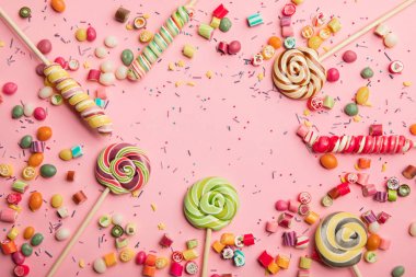 top view of delicious multicolored lollipops, caramel candies and sprinkles on pink background clipart