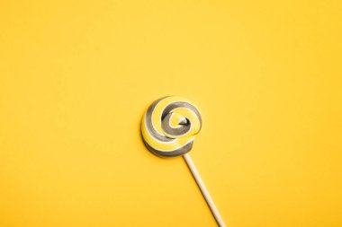 sarı arka plan üzerinde ahşap sopa üzerinde lezzetli çok renkli girdap lolipop üst görünümü