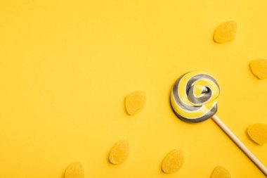 ahşap sopa ve sarı arka plan üzerinde jöle lezzetli çok renkli girdap lolipop üst görünümü