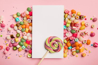 pembe arka plan üzerinde kopya alanı ile lezzetli şekerler, lolipop ve beyaz kart üst görünümü