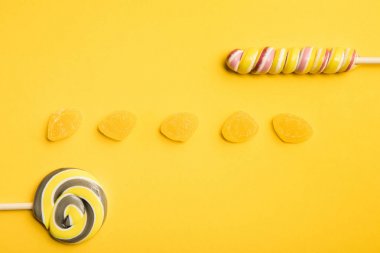 sarı arka planda lezzetli jöle ve çok renkli lolipop üst görünümü