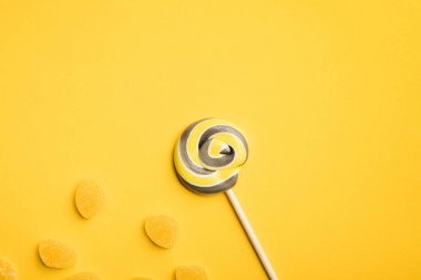 ahşap sopa ve sarı arka plan üzerinde jöle lezzetli yuvarlak lolipop üst görünümü