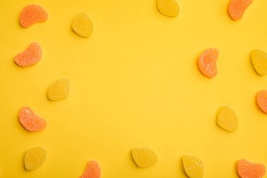 sarı arka plan üzerinde dağınık lezzetli portakal ve limon jöle üst görünümü