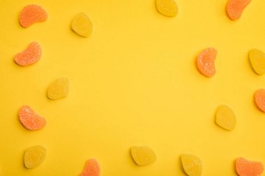 top view of delicious orange and lemon jellies scattered on yellow background clipart