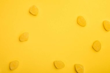 top view of delicious lemon jellies scattered on yellow background clipart