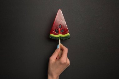 siyah arka plan üzerinde karpuz lezzetli lolipop tutan kadın kırpılmış görünümü