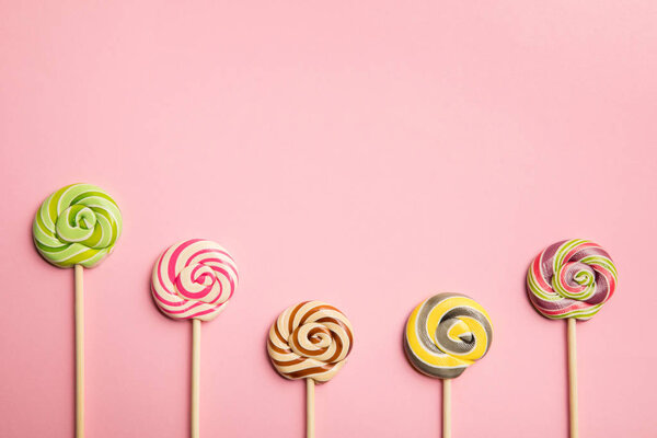 top view of delicious multicolored lollipops on wooden sticks on pink background