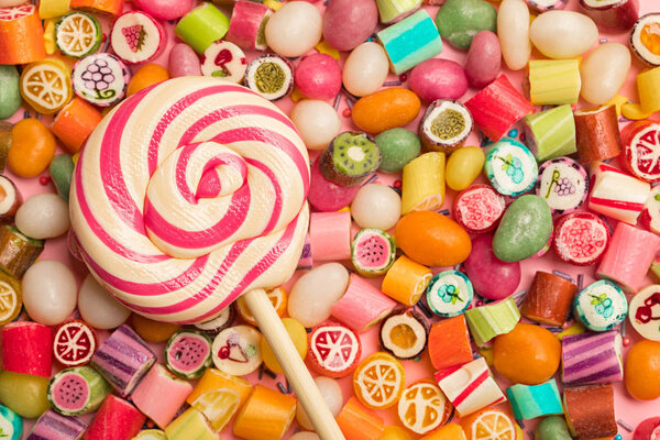 вид сверху на яркие вкусные разноцветные карамельные конфеты и леденец
