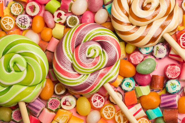 вид сверху на яркие вкусные разноцветные карамельные конфеты и леденцы на деревянных палочках
