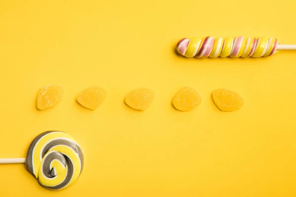 노란색 배경에 맛있는 젤리와 빛깔의 롤리팝의 상단보기 — 스톡 사진