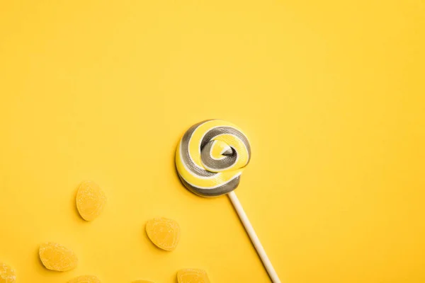 노란색 배경에 막대기와 젤리에 맛있는 롤리팝의 상단보기 — 스톡 사진