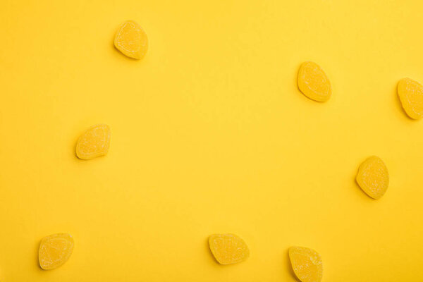top view of delicious lemon jellies scattered on yellow background