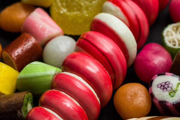 Крупный план ярких леденцов среди разноцветных конфет
